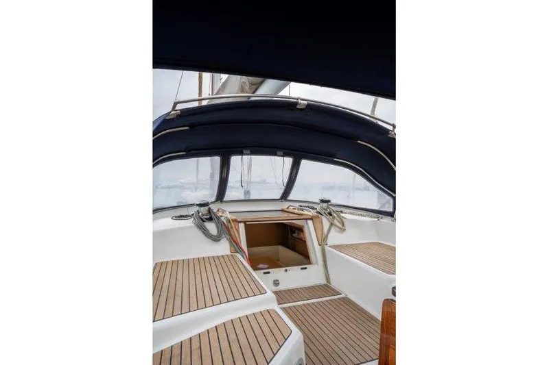  Yacht Photos Pics Cockpit of 2010 Jeanneau 53 sailboat with wooden deck and blue canopy.
