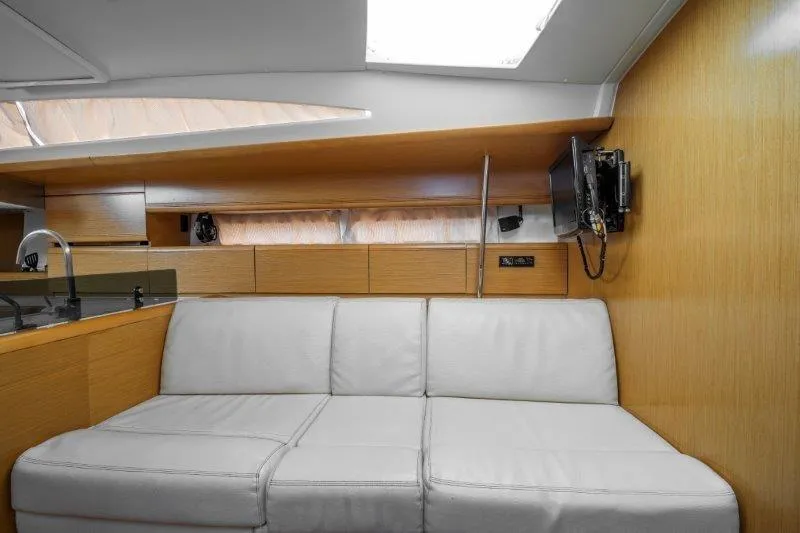  Yacht Photos Pics Interior of 2010 Jeanneau 53 yacht with white sofa and wooden paneling.