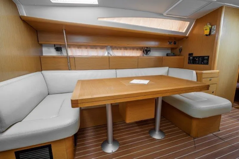  Yacht Photos Pics Interior of 2010 Jeanneau 53 yacht with wooden dining area and cushioned seating.