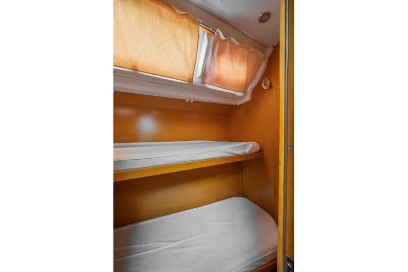  Yacht Photos Pics Interior cabin of 2010 Jeanneau 53 yacht with wooden bunk beds and curtains.