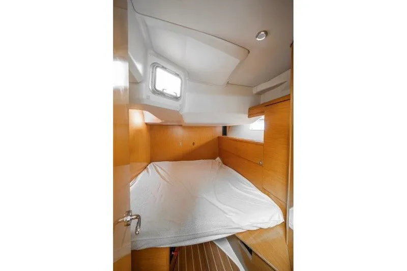  Yacht Photos Pics Cozy cabin interior of 2010 Jeanneau 53 sailboat with wooden finish and bedding.