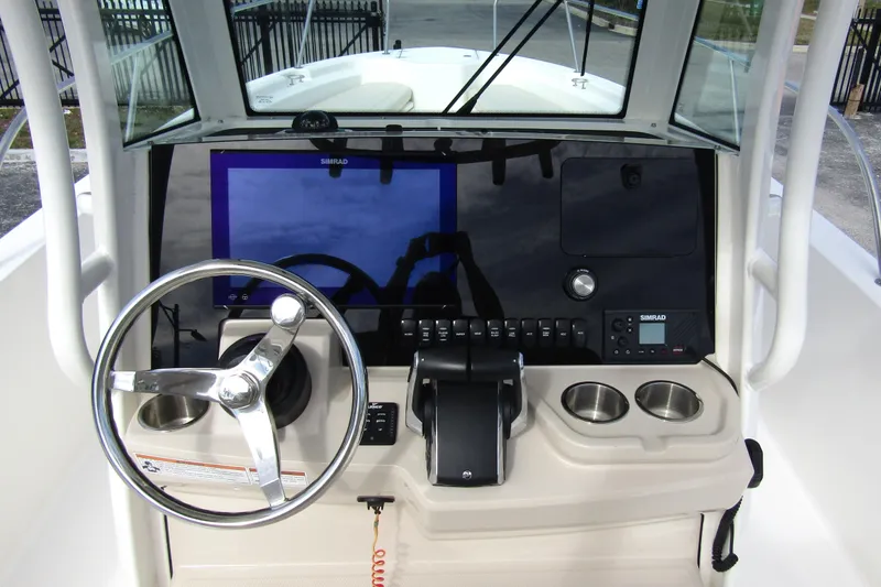  Yacht Photos Pics 2023 Boston Whaler 280 Dauntless helm with steering wheel, Simrad display, and cup holders.