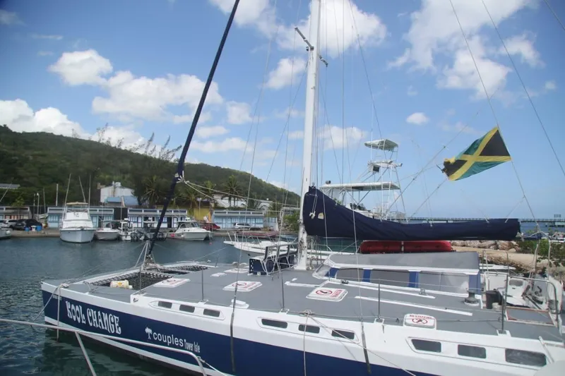 Kool Change Yacht Photos Pics Custom 1984 Spronk Day Charter Catamaran docked, Jamaican flag, blue sky, marina background.