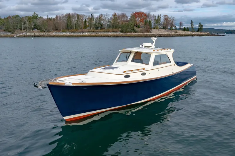 Lab Adore Yacht Photos Pics 2003 Hinckley Picnic Boat EP cruising on calm waters near a wooded shoreline.
