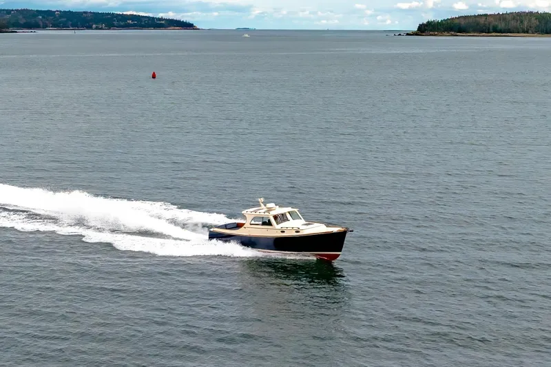 Lab Adore Yacht Photos Pics 2003 Hinckley Picnic Boat EP cruising on open water with scenic coastline.
