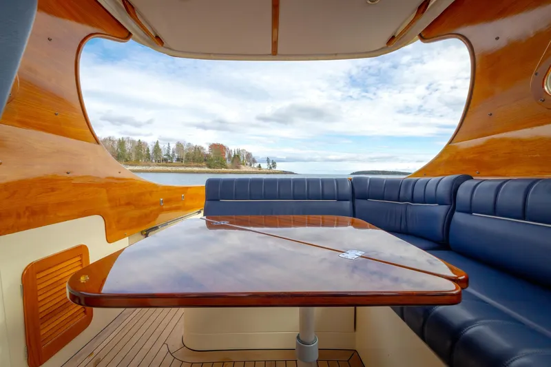 Lab Adore Yacht Photos Pics Interior of 2003 Hinckley Picnic Boat EP with wooden table and blue seating, overlooking scenic water view.