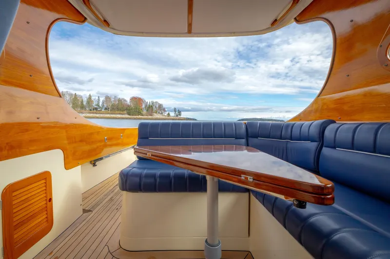 Lab Adore Yacht Photos Pics Interior of 2003 Hinckley Picnic Boat EP with blue seating and wooden accents, overlooking scenic water.