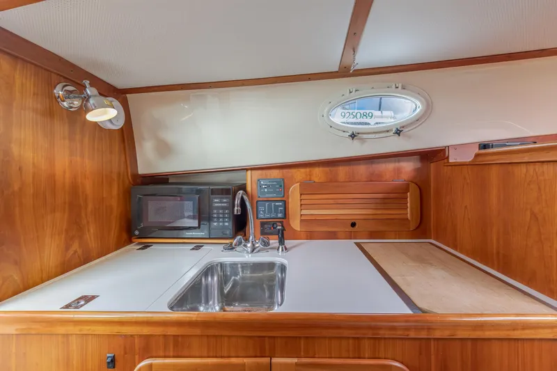Lab Adore Yacht Photos Pics 2003 Hinckley Picnic Boat EP interior kitchen with sink, microwave, and wooden cabinetry.