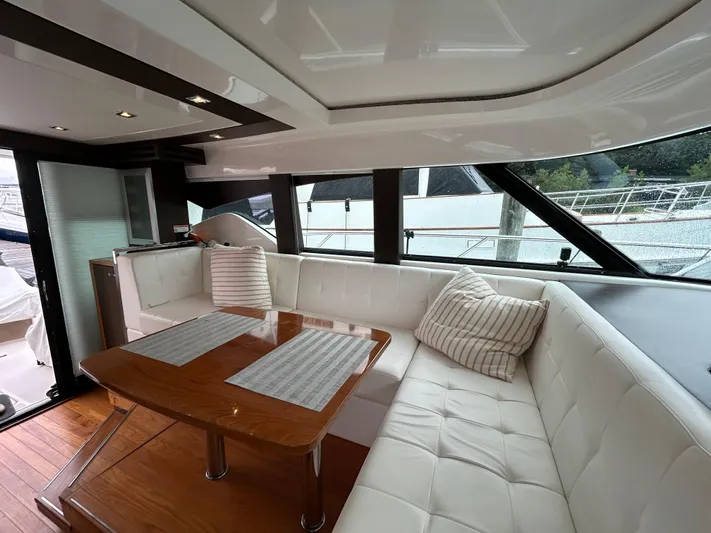  Yacht Photos Pics Luxurious interior of 2015 Tiara Yachts C44 Coupe with white seating and wooden table.