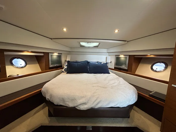  Yacht Photos Pics Luxurious bedroom interior of 2015 Tiara Yachts C44 Coupe with cozy bedding and porthole windows.
