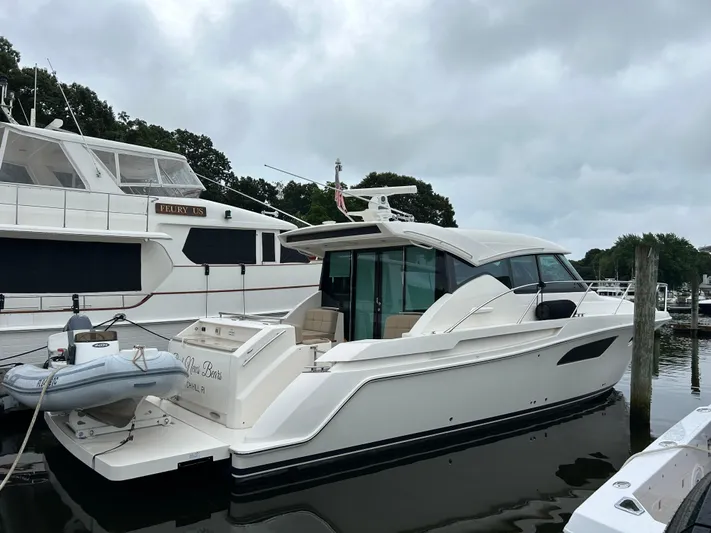  Yacht Photos Pics 2015 Tiara Yachts C44 Coupe docked beside another yacht on a cloudy day.