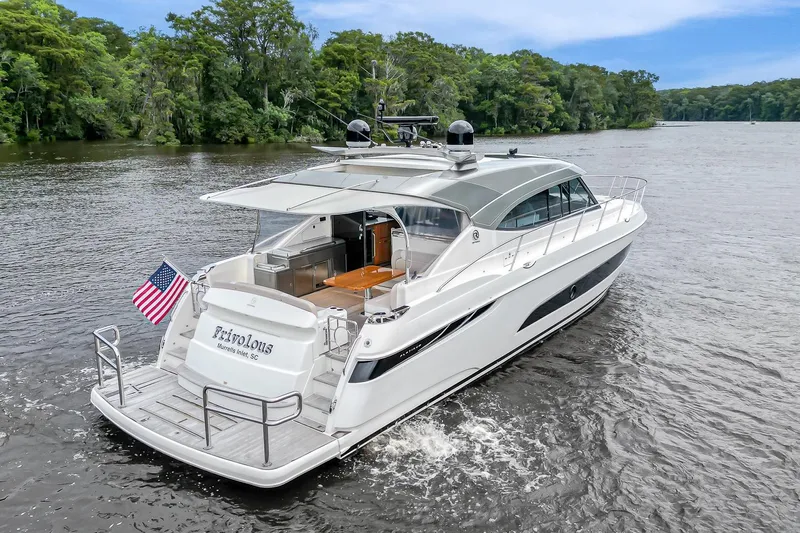Frivolous Yacht Photos Pics 2021 Riviera 5400 Sport Yacht Platinum Edition cruising on a scenic river.