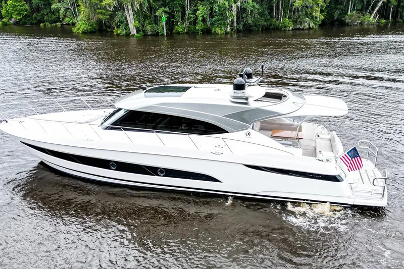 Frivolous Yacht Photos Pics 2021 Riviera 5400 Sport Yacht Platinum Edition cruising on a serene river.