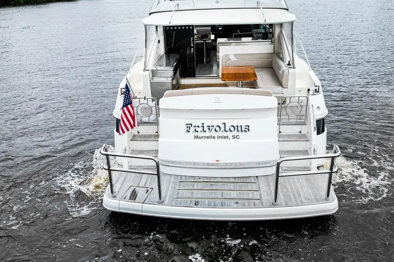 Frivolous Yacht Photos Pics 2021 Riviera 5400 Sport Yacht Platinum Edition on water, rear view with American flag.