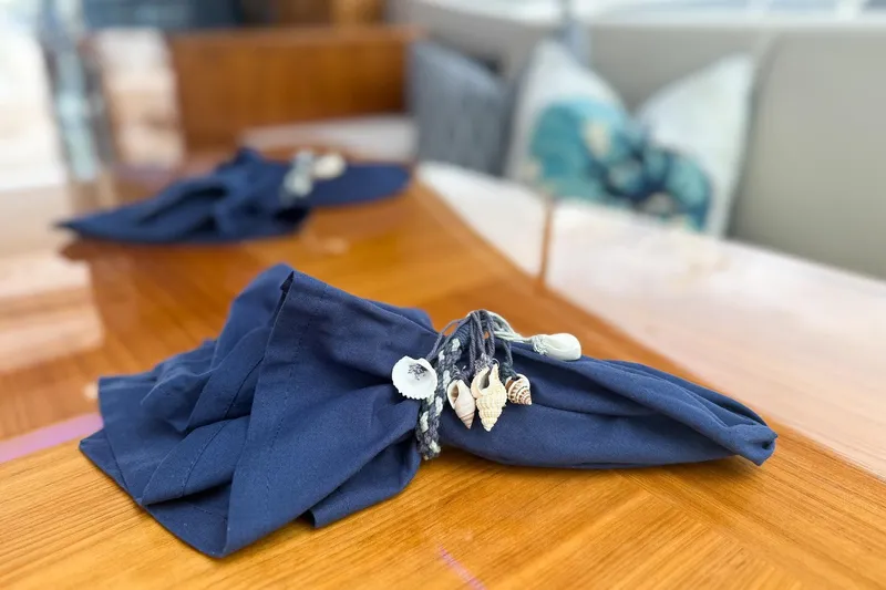 Frivolous Yacht Photos Pics Nautical-themed napkin with seashells on Riviera 5400 Sport Yacht's wooden table, 2021 model.