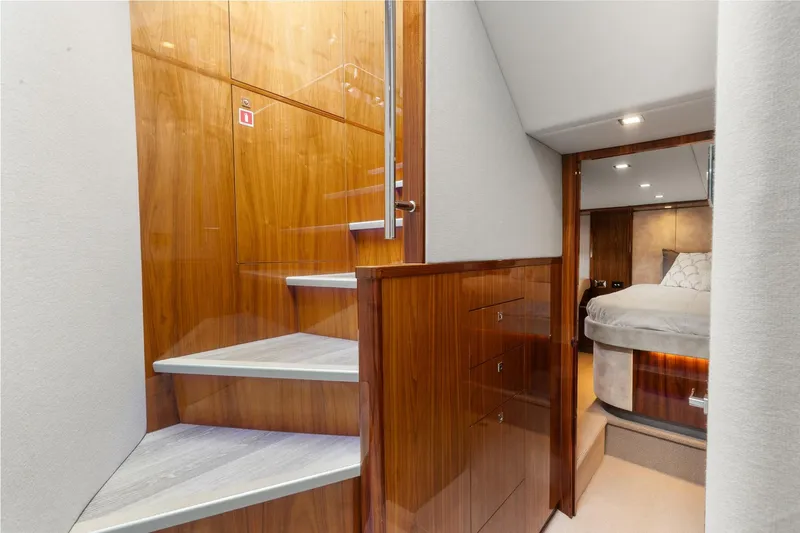 Frivolous Yacht Photos Pics Interior of 2021 Riviera 5400 Sport Yacht Platinum Edition, featuring wooden stairs and a cozy bedroom.