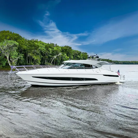 Frivolous Yacht Photos Pics 2021 Riviera 5400 Sport Yacht Platinum Edition cruising on a scenic river.