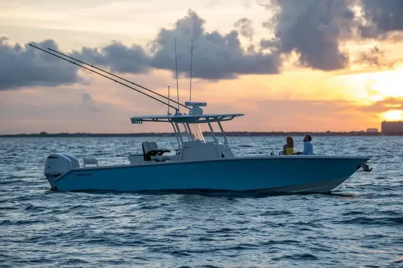 In Stock Yacht Photos Pics 2026 Jupiter 32 boat on water at sunset, featuring fishing rods and two people onboard.