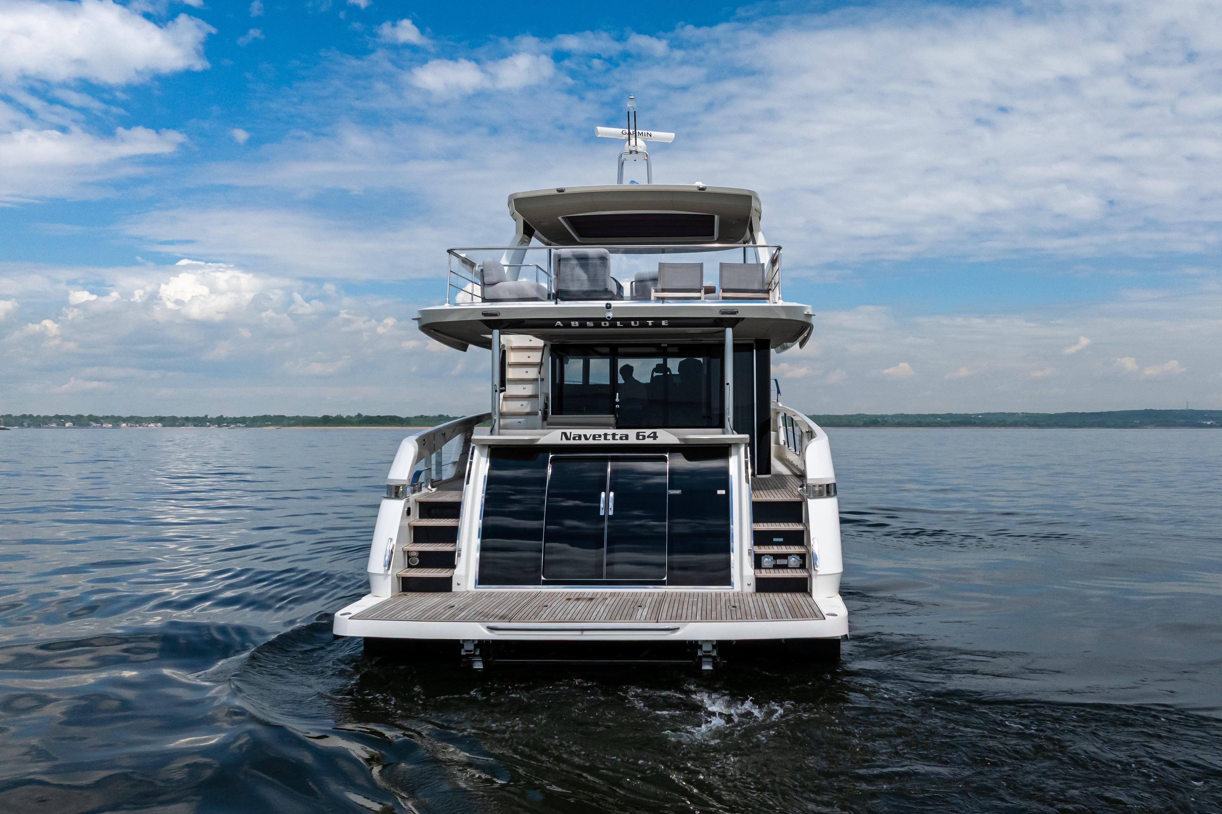 2025 Absolute Navetta 64 yacht on calm water under a partly cloudy sky.