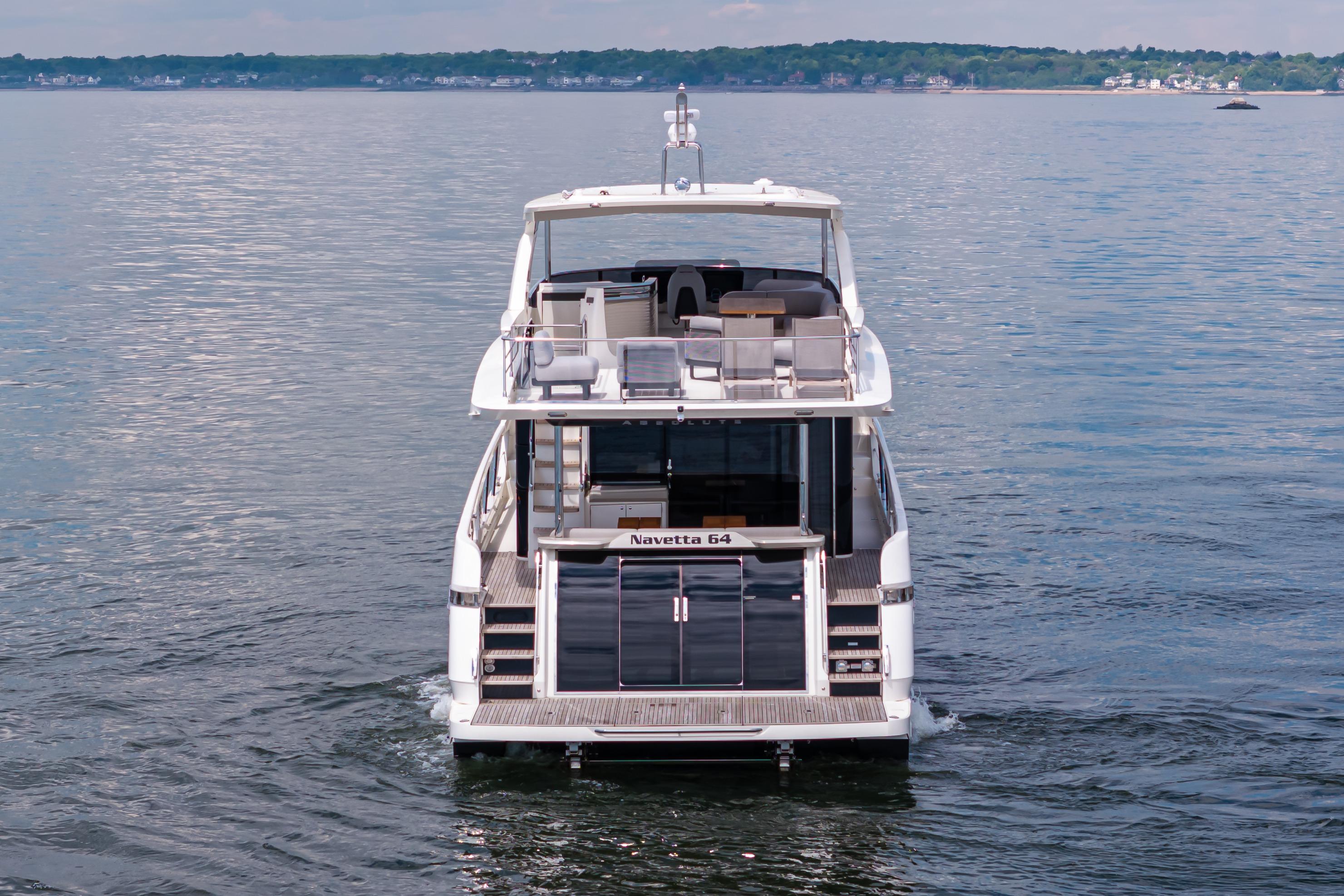 2025 Absolute Navetta 64 yacht cruising on calm waters, rear view.