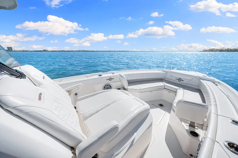 Tt Aloan At Last Yacht Photos Pics 2023 Fountain 32 NX boat interior with white seating, ocean view, and blue sky.