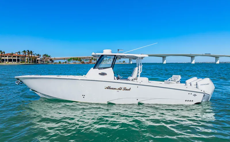 Tt Aloan At Last Yacht Photos Pics 2023 Fountain 32 NX boat on clear blue water near a bridge.