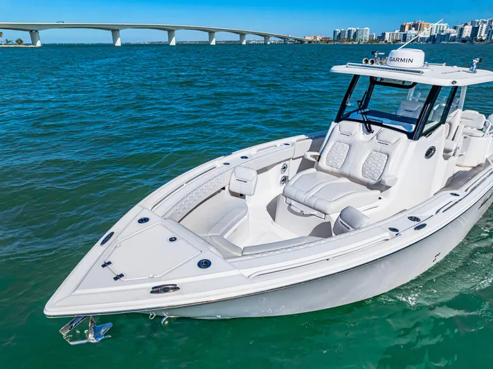 Tt Aloan At Last Yacht Photos Pics 2023 Fountain 32 NX boat cruising on blue water near a bridge.