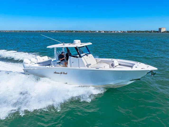 Tt Aloan At Last Yacht Photos Pics 2023 Fountain 32 NX boat cruising on open water under clear blue skies.