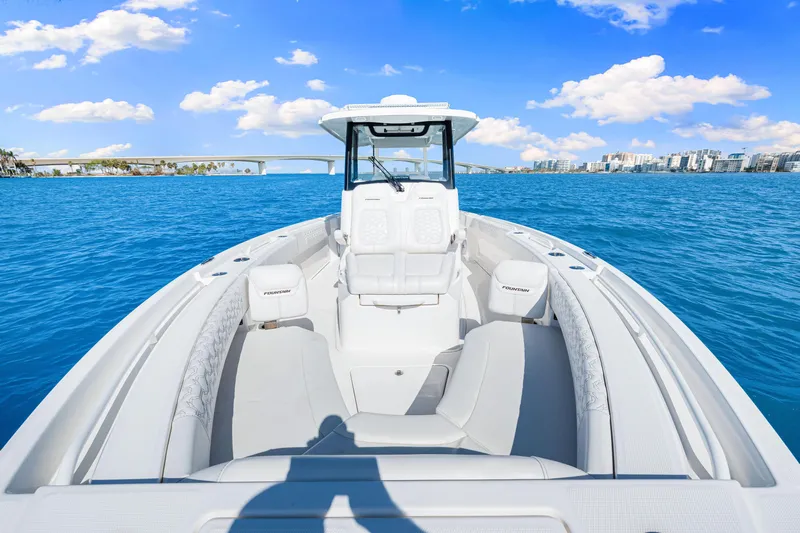 Tt Aloan At Last Yacht Photos Pics 2023 Fountain 32 NX boat on blue water with city skyline and bridge in background.