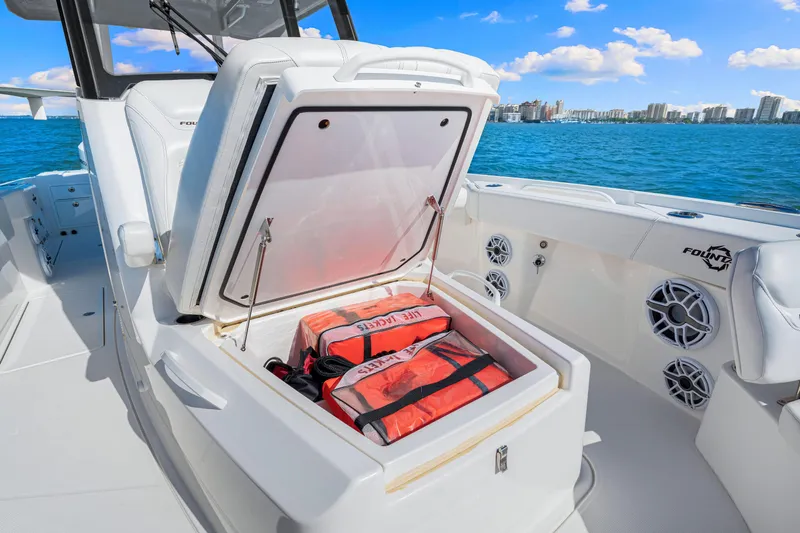 Tt Aloan At Last Yacht Photos Pics 2023 Fountain 32 NX boat with open storage compartment, life jackets visible, ocean backdrop.