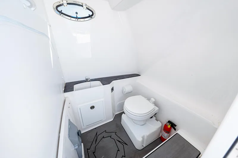 Tt Aloan At Last Yacht Photos Pics 2023 Fountain 32 NX boat bathroom with toilet, sink, and fire extinguisher.