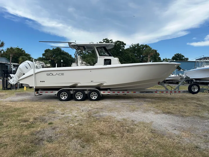 Yacht Photos Pics 2024 Solace 32 CS boat on trailer, parked outdoors under a partly cloudy sky.