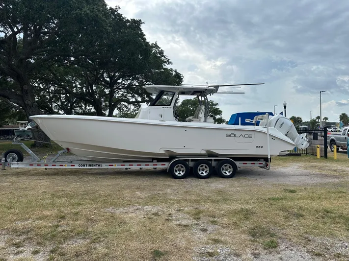  Yacht Photos Pics 2024 Solace 32 CS boat on trailer, parked outdoors under cloudy sky.