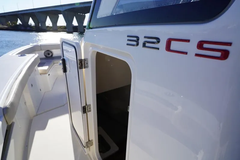  Yacht Photos Pics 2024 Solace 32 CS boat with open cabin door, near a bridge on the water.