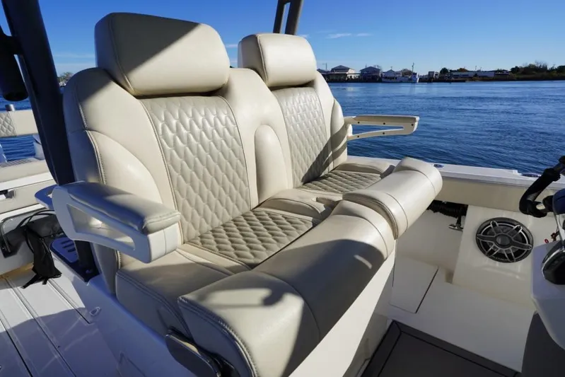  Yacht Photos Pics Luxurious seating on 2024 Solace 32 CS boat, featuring quilted upholstery and armrests, with scenic water view.
