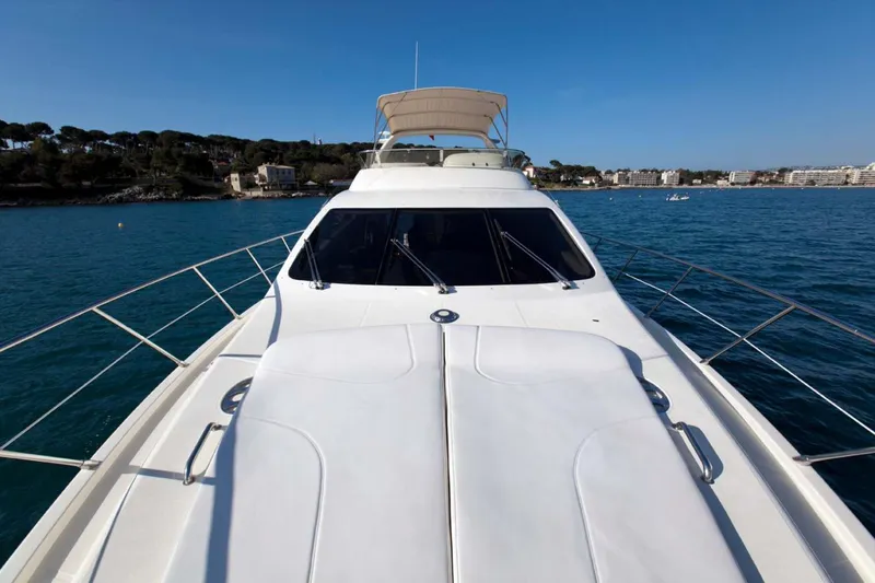  Yacht Photos Pics 2006 Azimut 62 yacht cruising on clear blue waters near a coastal town.