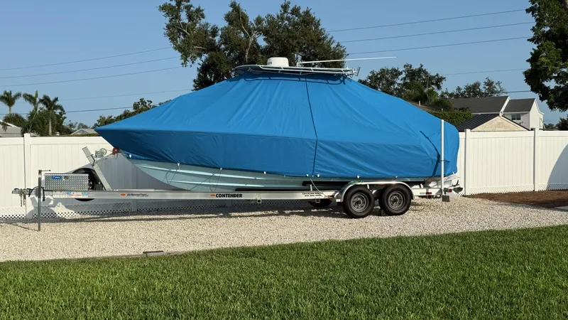  Yacht Photos Pics 2023 Contender 25 Tournament boat covered in blue tarp on a trailer, parked outdoors.