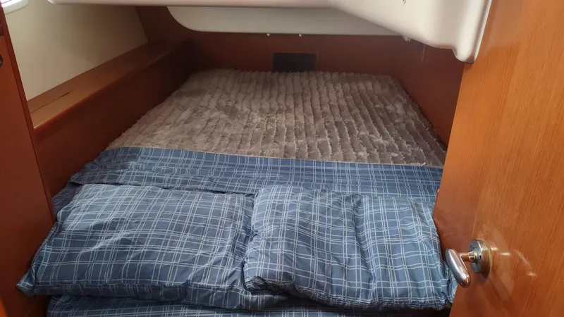 Tiffany Nicole Yacht Photos Pics Cozy cabin bed in 2011 Beneteau Oceanis 43 Family sailboat, featuring blue plaid bedding.