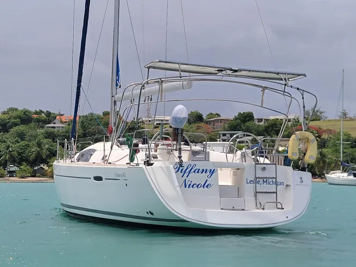 Tiffany Nicole Yacht Photos Pics 2011 Beneteau Oceanis 43 Family sailboat on turquoise water, lush green shoreline in background.