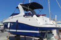 2008 Rinker 260 boat with blue and white hull, docked on land.