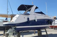2008 Rinker 260 boat on dry dock, blue and white hull, with canopy.