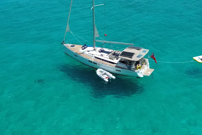 Lazy Days Yacht Photos Pics 2015 Jeanneau Sun Odyssey 469 sailboat anchored in clear turquoise water.