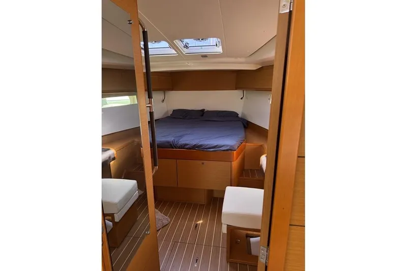 Lazy Days Yacht Photos Pics Interior cabin of 2015 Jeanneau Sun Odyssey 469 sailboat, featuring a cozy bed and wooden furnishings.