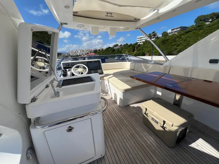 Lula Yacht Photos Pics Luxurious 2016 Azimut 54fly yacht interior with seating, table, and helm under a sunny sky.