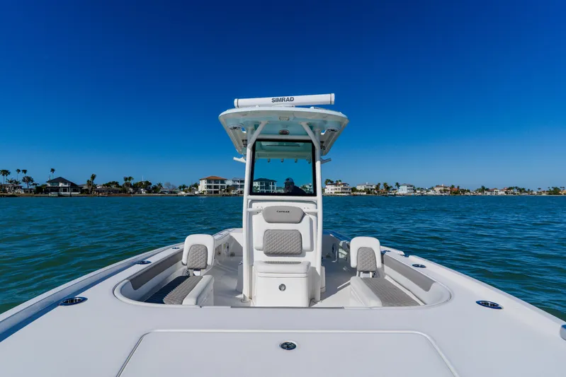  Yacht Photos Pics 2022 Caymas 28 HB boat cruising on clear blue water near coastal homes.