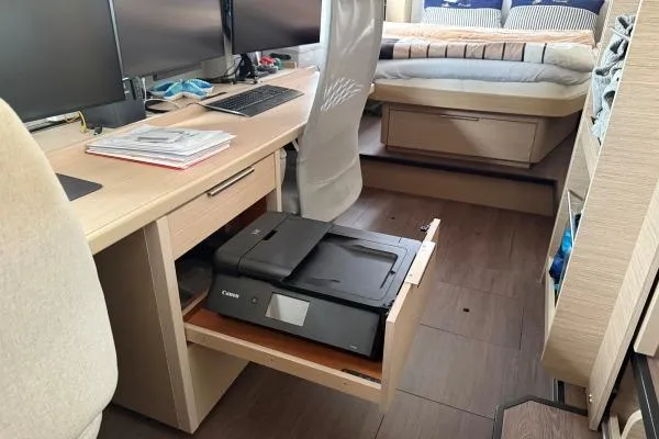 Tomcat Yacht Photos Pics Modern office setup inside a 2023 Lagoon 46 yacht with printer and dual monitors.