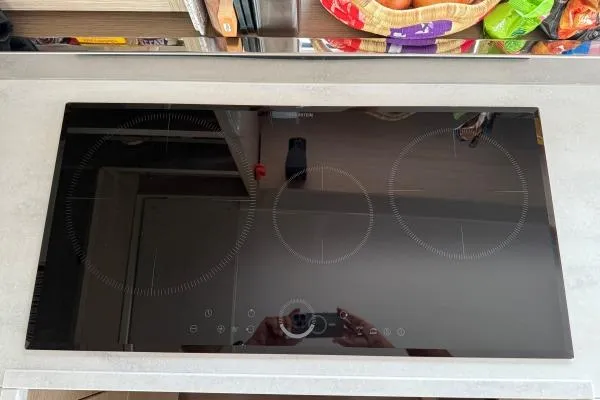 Tomcat Yacht Photos Pics Modern induction cooktop with three burners on a sleek kitchen countertop.