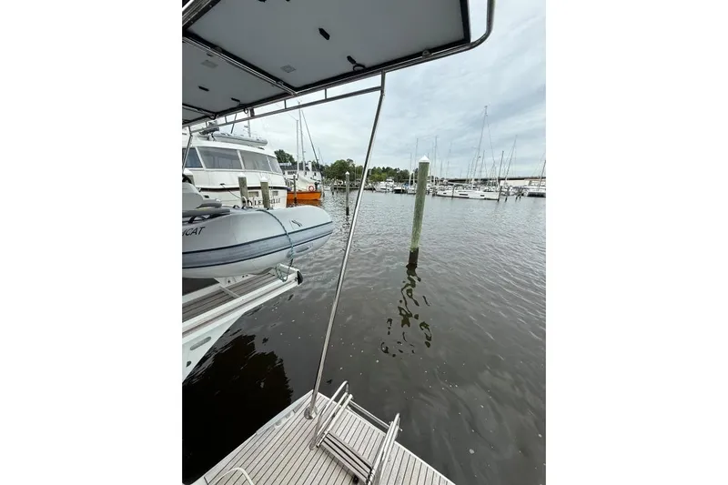 Tomcat Yacht Photos Pics 2023 Lagoon 46 yacht docked at marina with inflatable boat and calm waters.