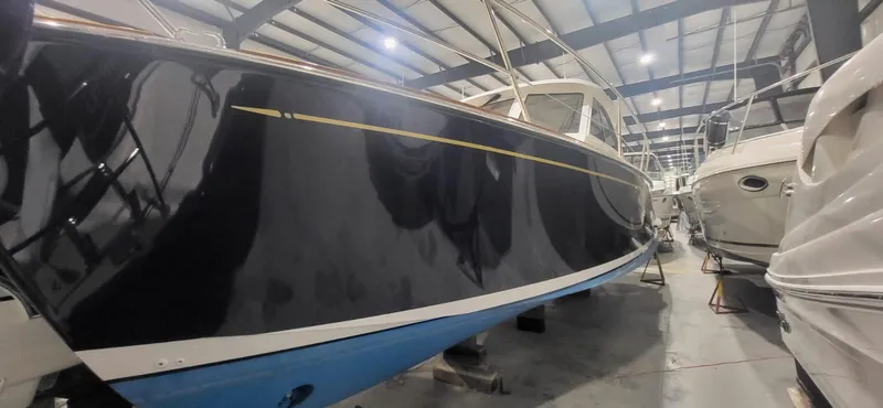  Yacht Photos Pics 2022 Legacy 36 boat in storage, sleek black hull, indoor facility.