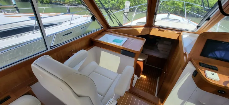  Yacht Photos Pics 2022 Legacy 36 boat interior with helm, white seating, and wood accents.